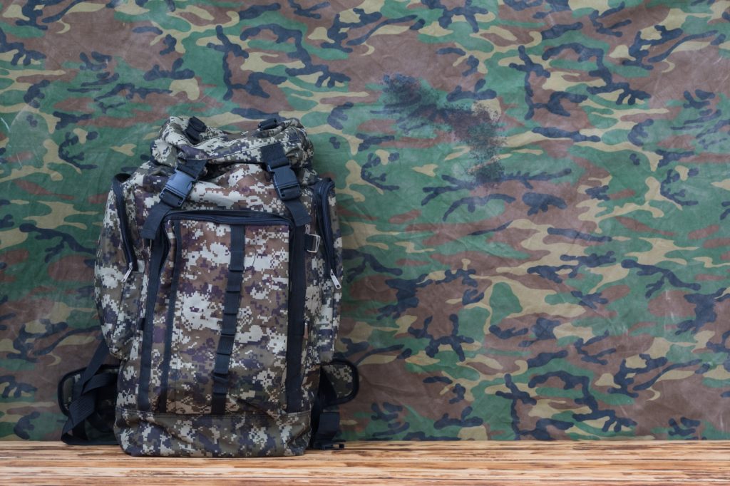 Militärischer Rucksack an Camouflage-Wand